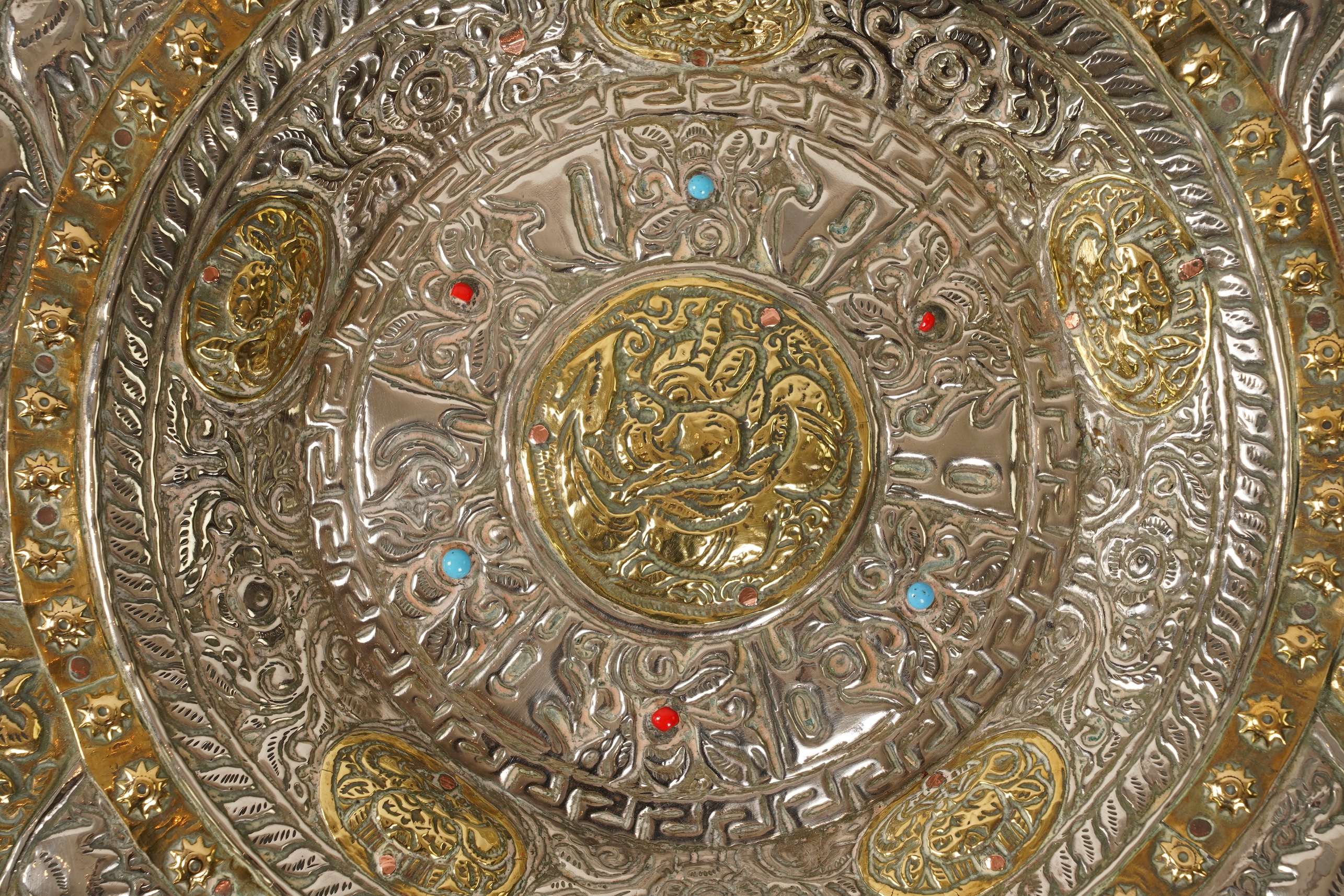 A graduated set of three Nepalese repoussé white metal and brass chargers, first half 20th century